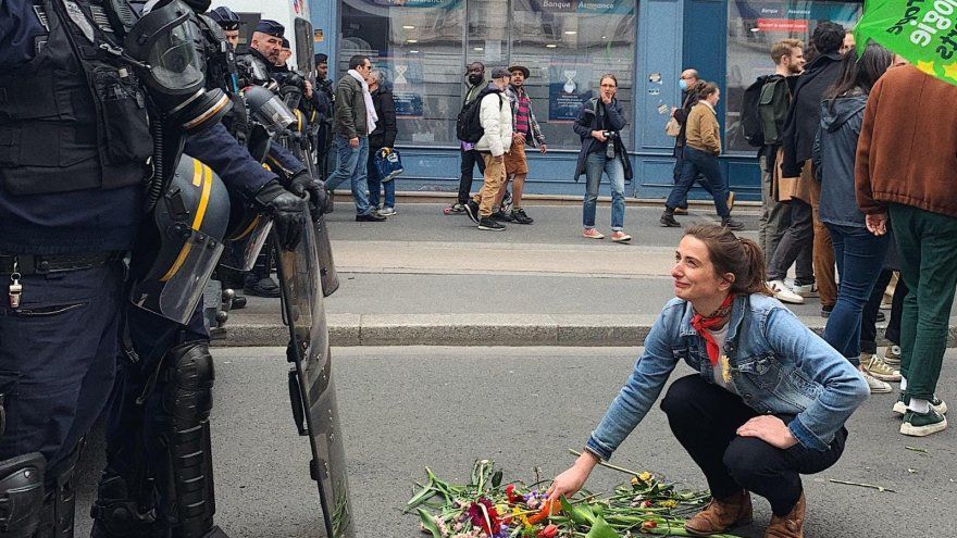 Marine Tondelier agenouillée devant un tas de fleurs face à la police.
